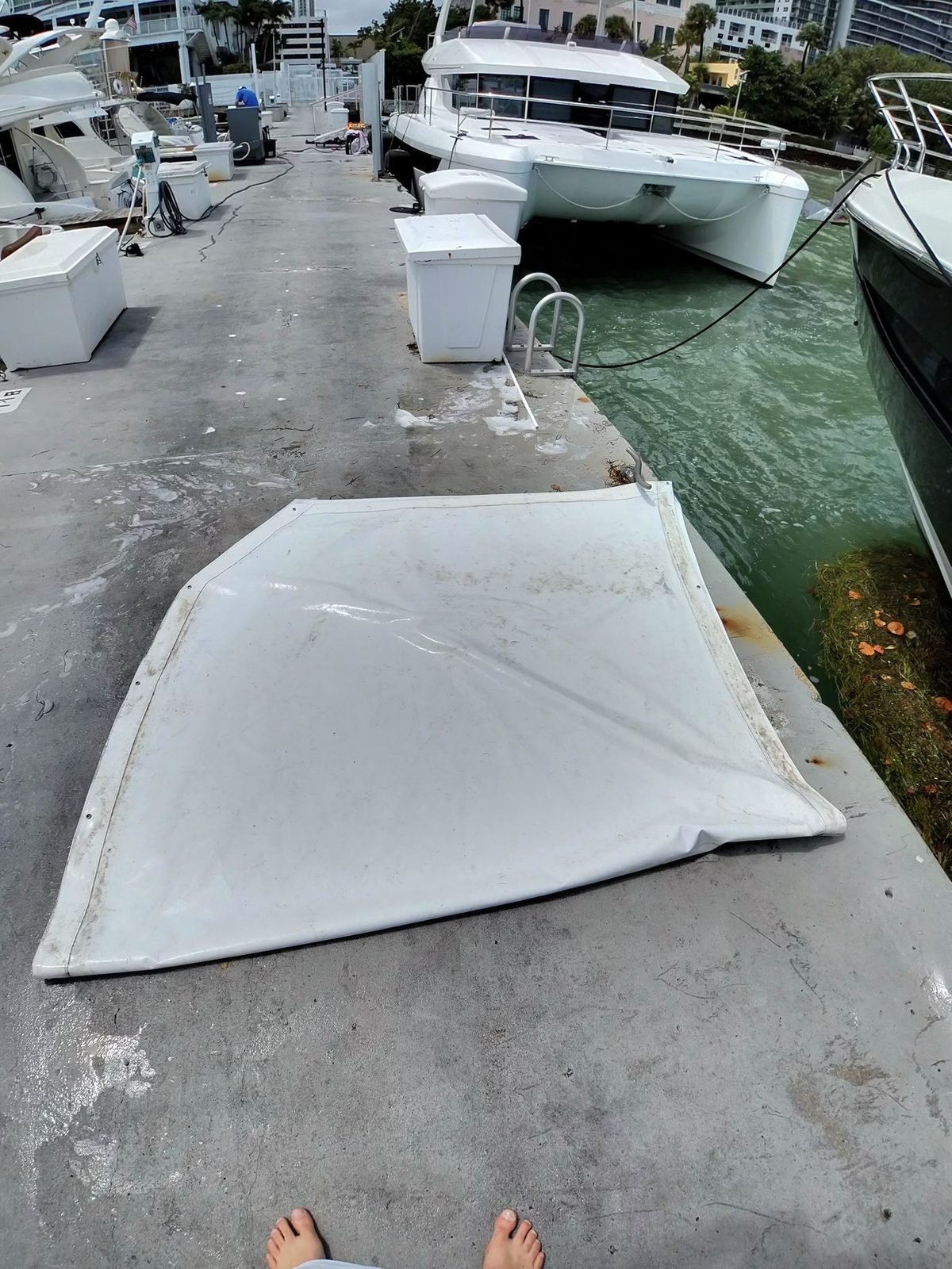 Weathered canvas bimini top before cleaning, laid out dockside